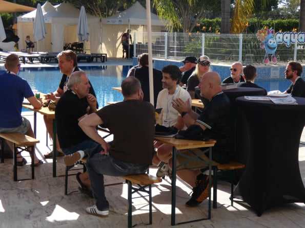 Attendees talking business at tables by the pool