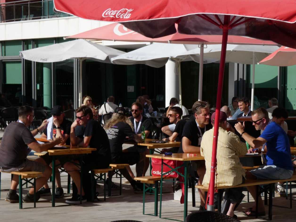 Attendees meeting at tables under parasols on the hotel terrace